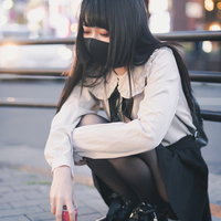 路上でぴえん女子、黒いマスク姿でしゃがみこむの写真
