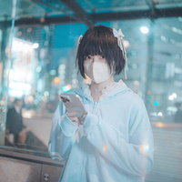 終電を逃した夜間の駅前でスマホを見るマスク姿の若い女性の写真