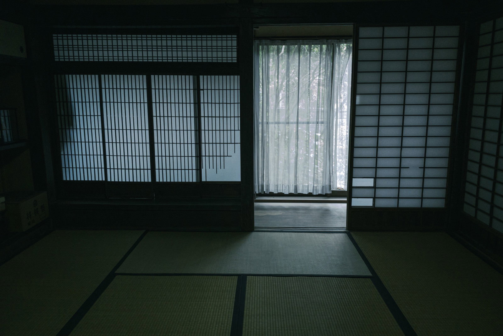畳敷きの和室で窓際に白いカーテンが下がっている室内風景