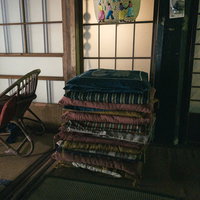 畳の上に積み重ねられた古い座布団と昭和の生活空間の写真