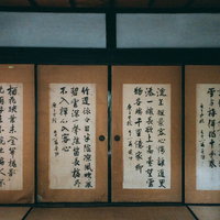 古い襖を背景に並ぶ漢文の書。格調高い墨字が表現された和室の掛け軸の写真