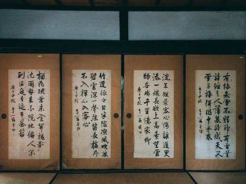 古い襖を背景に並ぶ漢文の書。格調高い墨字が表現された和室の掛け軸