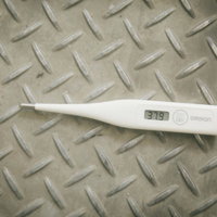 足場板に置かれた体温計の37.9度表示の写真