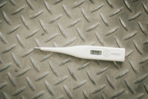 足場板に置かれた体温計の37.9度表示