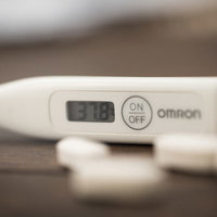 37.8度の高熱を示すデジタル体温計と錠剤の写真