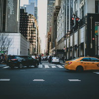 ニューヨーク市街を走る黄色いタクシーと高層ビルの街並みの写真