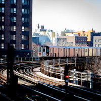 ニューヨークの市街地を走る高架電車とレンガ造りのビル群の写真