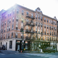 ニューヨークの街角に建つレンガ造りのアパートメント建物の写真