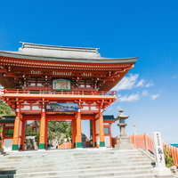 青空を背景に立つ宮崎県日南市の鵜戸神宮の朱色の楼門の写真