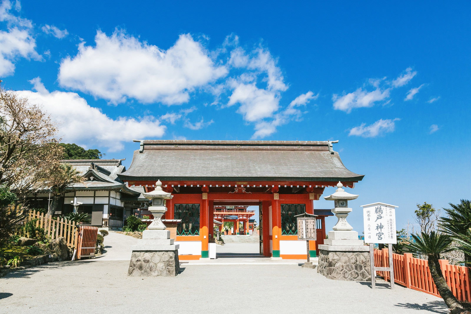 青空を背景にした鵜戸神宮の朱塗りの神門と境内の様子