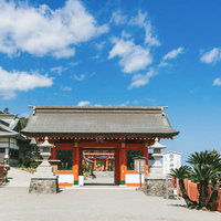 青空を背景にした鵜戸神宮の朱色の神門と狛犬の写真