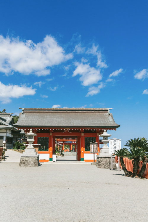 青空を背景にした鵜戸神宮の朱色の神門と狛犬