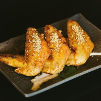 みやざき地頭鶏の大きな手羽先、白ごまをまぶした焼き鳥の写真