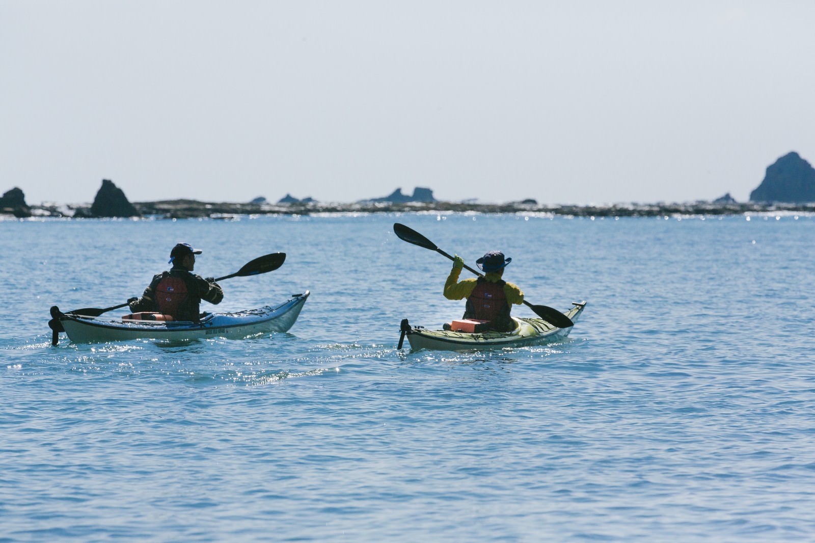 Two people paddling sea kayaks on the blue ocean