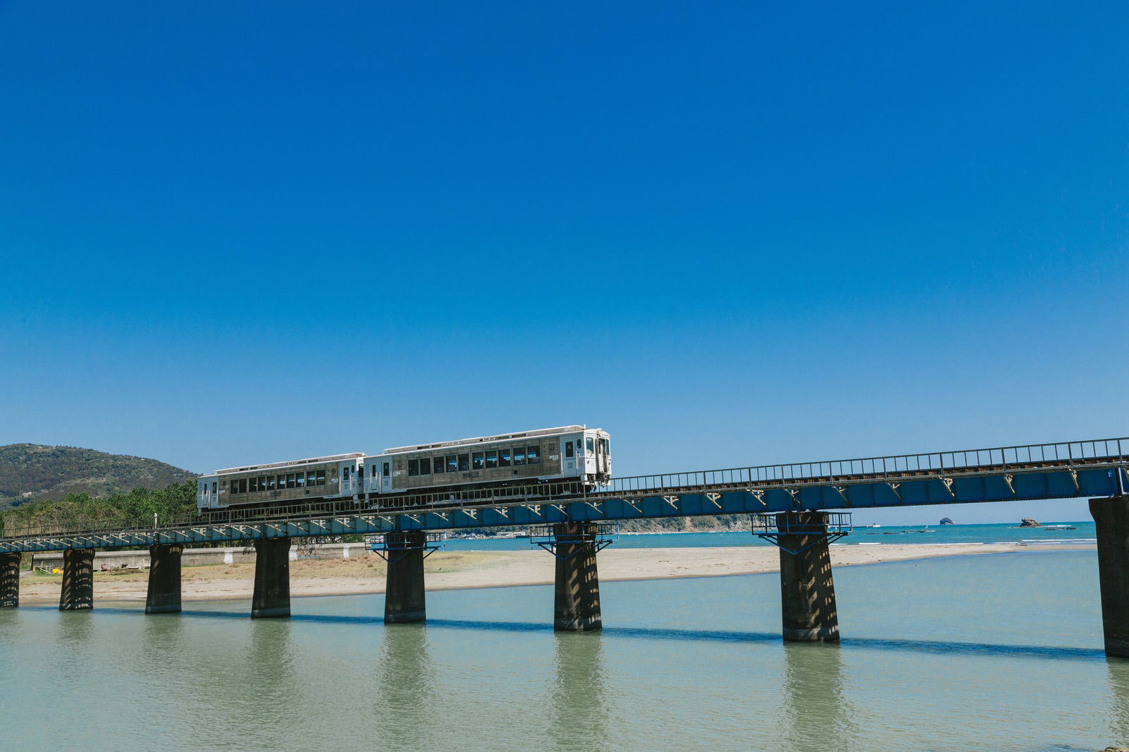 青空の下、橋を渡る海幸山幸の観光列車