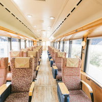 飫肥杉の温かみある座席が並ぶ観光列車「海幸山幸」の車内の写真