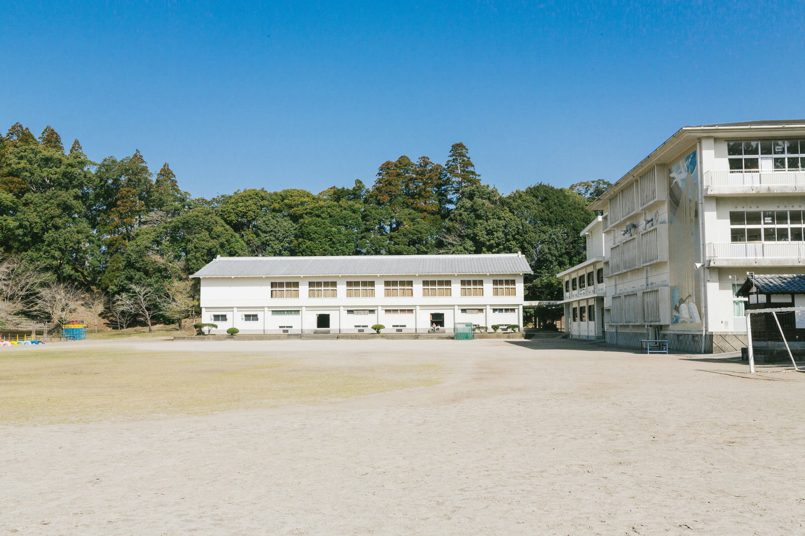 青空の下に広がる飫肥城小学校の校庭と白い校舎建物