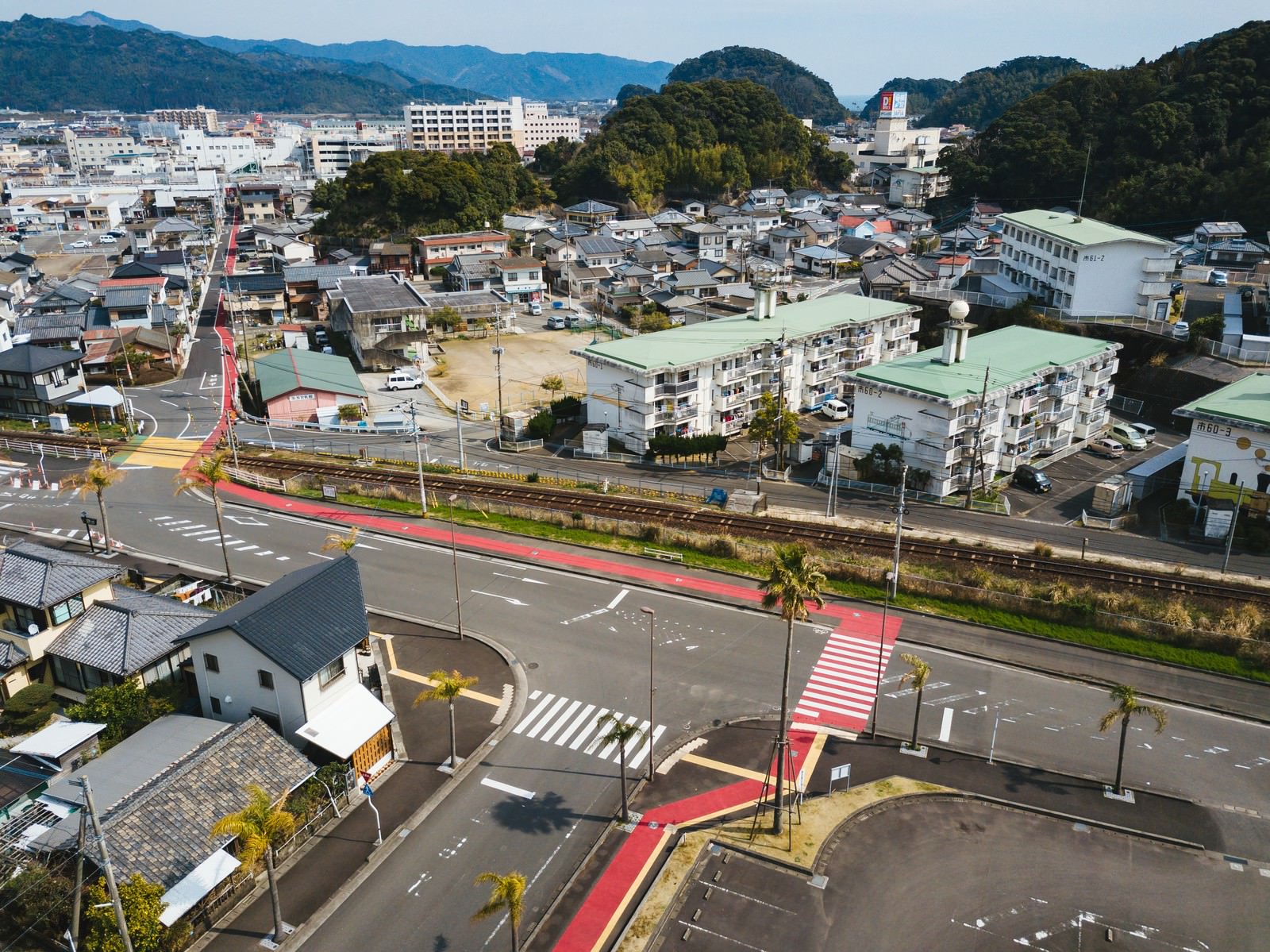 山間の街並みに赤い歩道が延びる天福球場から油津商店街への道