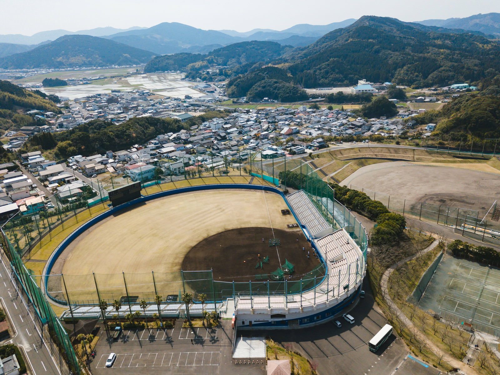 日南市の南郷スタジアムを空撮した風景、緑に囲まれた球場と町並み