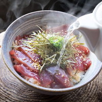 熱々の出汁を注いで完成する鰹めしの丼の写真