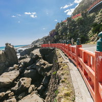鵜戸神宮の朱色の玉垣と海岸の絶壁、青空と海の写真