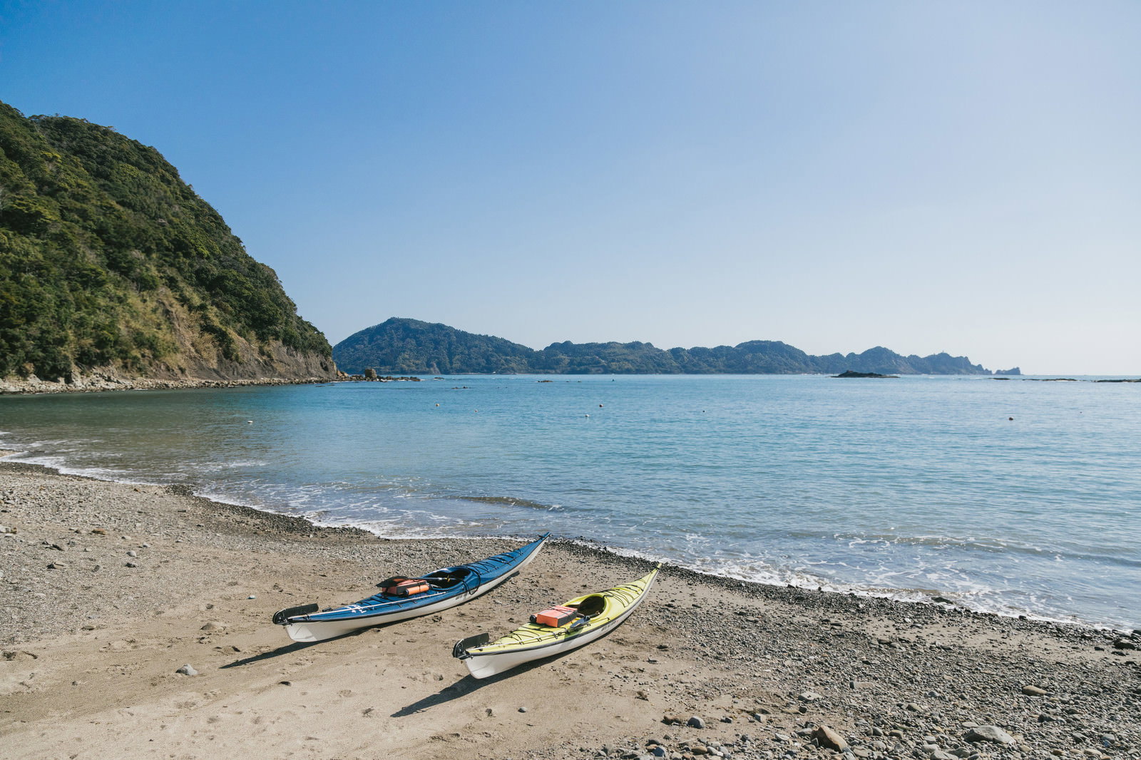 青い海と空の下、栄松ビーチの砂浜に2艇のシーカヤックが停泊している