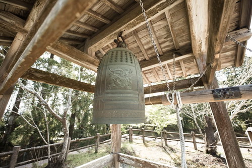 飫肥城跡に吊り下げられた青銅色の鐘と木造建築