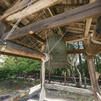 飫肥城の木造鐘楼に吊り下げられた古い鐘と城跡の風景の写真