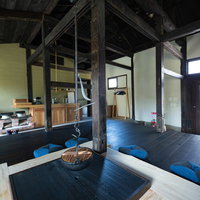 青い囲炉裏が中央に配置された古民家宿の室内の写真