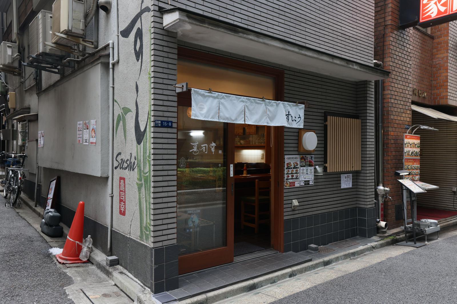 白い暖簾がかかった寿司屋の店前に三角コーンが置かれている