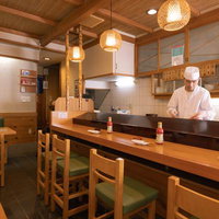 カウンター内で仕込み作業をする寿司職人の調理風景の写真