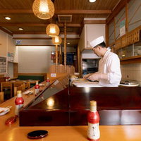 木目調の店内で寿司を握る職人の姿勢と調理風景の写真