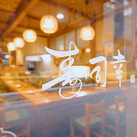 寿司幸の入口ドアのガラスに映る店内風景と照明の写真