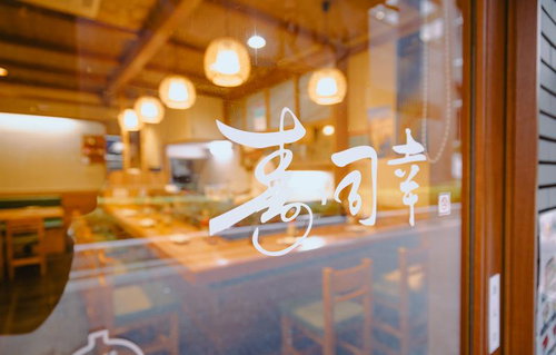 寿司幸の入口ドアのガラスに映る店内風景と照明