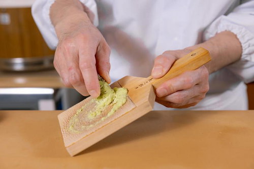 木製のおろし金でわさびをすりおろす寿司職人の手元