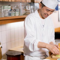 黒いまな板でわさびをおろす寿司職人の調理風景の写真