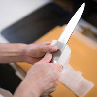 白いまな板の上で剥かれていく大根の桂剥きの写真