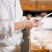 寿司職人が包丁で大根を桂剥きする職人技の写真