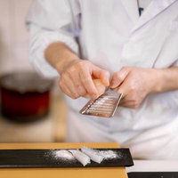 寿司職人がおろし金で刺身に岩塩をすりおろすの写真