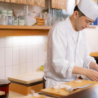 寿司職人が白い調理服と帽子で握り寿司を仕込む調理の瞬間の写真