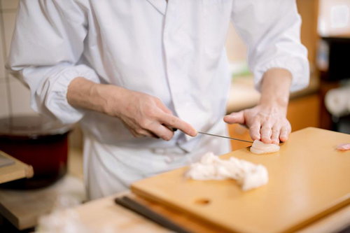 まな板の上でホタテを包丁で丁寧に切り分ける寿司職人の手さばき