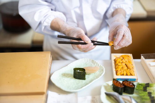 ウニを軍艦巻きに盛り付ける寿司職人の手元