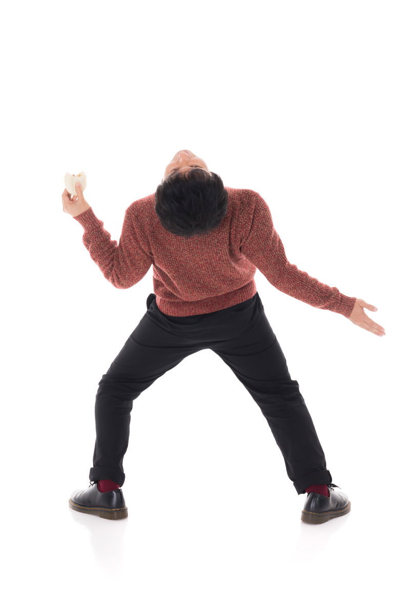 肉まんを食べながらイナバウアーポーズをする男性［モデル：大川竜弥］