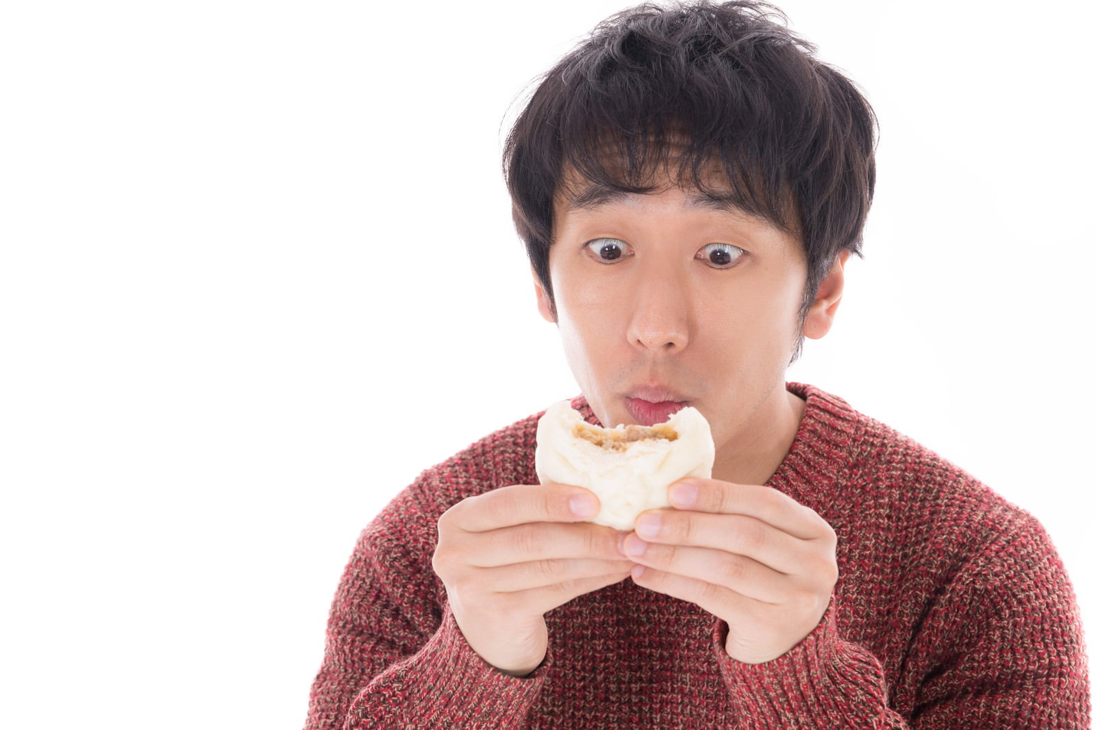赤いセーターを着た男性が肉まんを食べている［モデル：大川竜弥］
