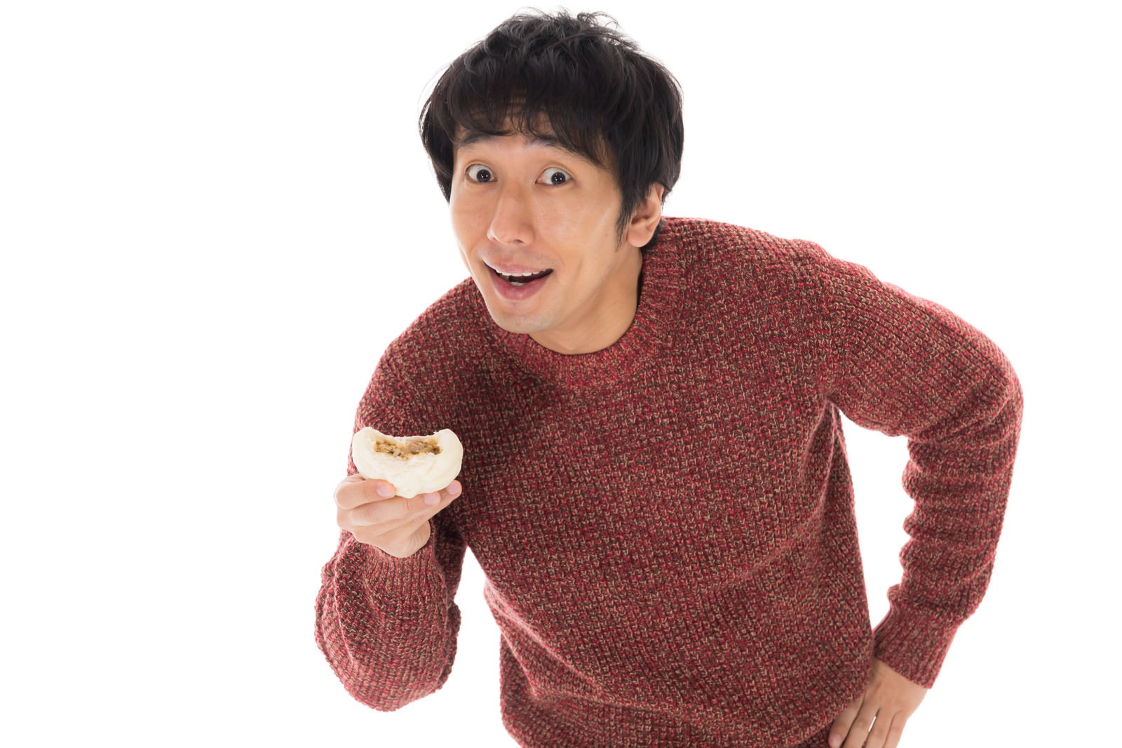 赤いニットを着た男性が肉まんを指差し、いたずらっぽく笑っている［モデル：大川竜弥］