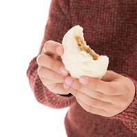 プレミアムな具材が詰まった肉まんを食べる男性の写真