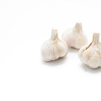 皮を剥く前の白いにんにく（3つ）の食材の写真