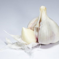 皮を剥いた生にんにくの房と分離した一片、薄皮の写真