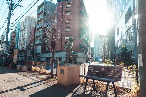 日暮里の街角に立つ響 Echo の銅像とベンチ