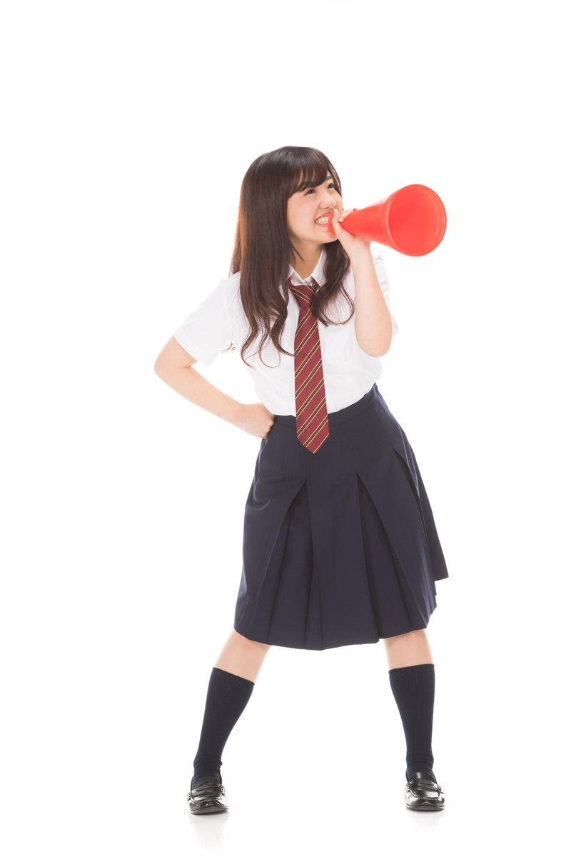 赤いメガホンを持って応援のポーズをとる制服姿の女子高生［モデル：河村友歌］